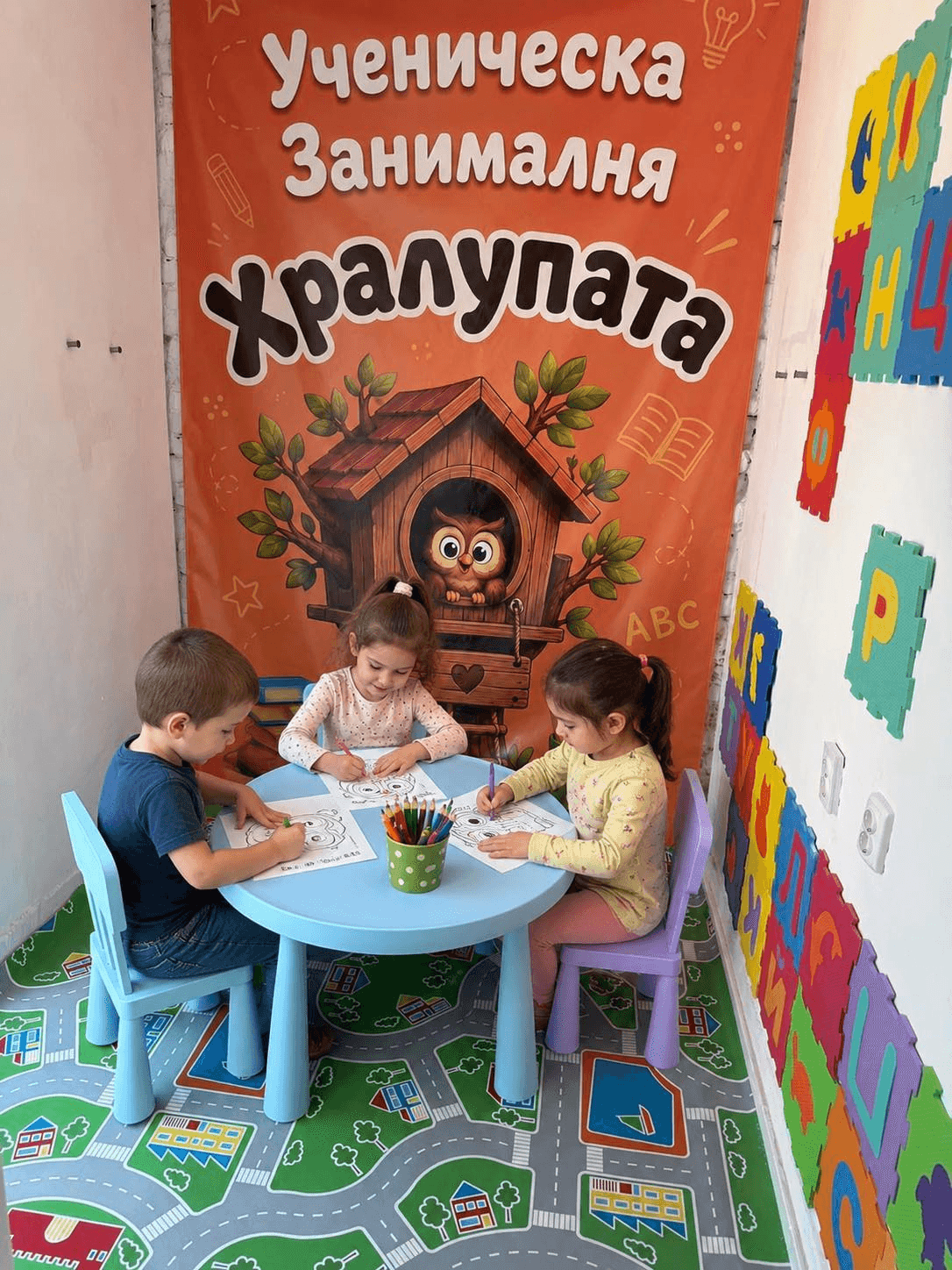 Малчугани рисуват пред банера на Хралупата